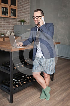 Handsome man wearing suit and underpants working at home online standing on the kitchen