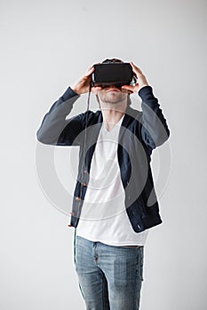 Handsome man wearing virtual reality glasses isolated on a gray background