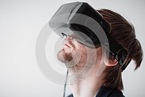 Handsome man wearing virtual reality glasses isolated on a gray background