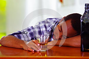 Handsome man wearing white blue shirt sitting by bar counter lying over desk drunk sleeping, alcoholic concept