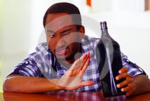 Handsome man wearing white blue shirt sitting by bar counter lying over desk expressing no desire to keep drinking using