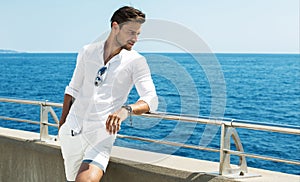 Handsome man wearing white clothes posing in sea scenery
