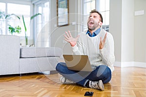 Handsome man wearing working using computer laptop celebrating mad and crazy for success with arms raised and closed eyes