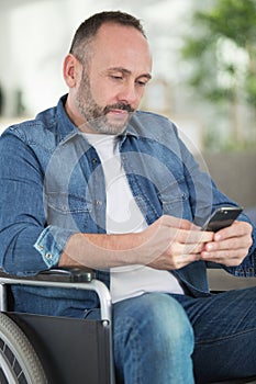 handsome man on wheelchair texting on smartphone