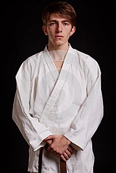 Handsome man in white kimono on a black background. Boy learning fighting techniques. Karate lessons concept.