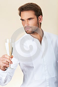 Handsome man in white shirt celebrating with a glass of champagne