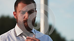 Handsome man in white shirt tying the necktie outdoors