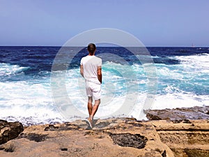 Handsome man in white stand on rock back looking at sea waves,calm down,fashion model,believe in hope,traveling tourist,feel free