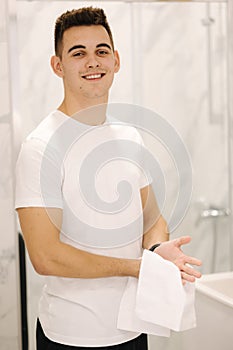 Handsome man wipes his hands with a white towel after washing. Light bath. Keep clean concept.