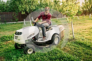 Handsome man, worker using grass cutting equipment for landscaping works