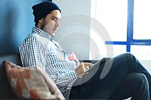 Handsome man working from his home office. Analyze business plans on laptop. Blurred background, film effect