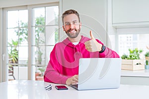 Handsome man working using computer laptop doing happy thumbs up gesture with hand