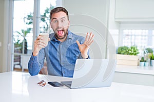 Handsome man working using computer laptop and drinking a cup of coffee very happy and excited, winner expression celebrating