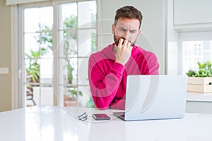 Handsome man working using computer laptop looking stressed and nervous with hands on mouth biting nails