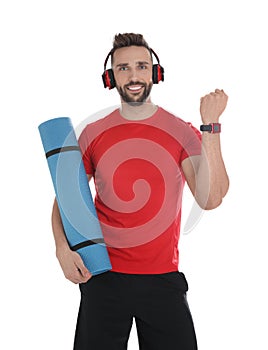 Handsome man with yoga mat and headphones showing smartwatches on white background