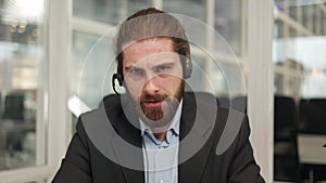 Handsome manager with headset making video call in creative office environment