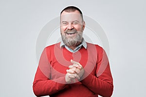 Handsome mature bearded man in red sweater laughing