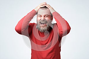 Handsome mature bearded man in red sweater laughing