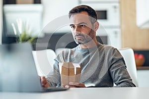 Handsome mature business man eating take away noodles while working with laptop at home