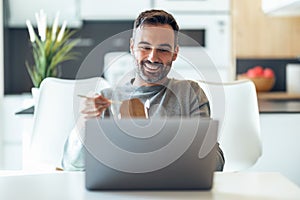 Handsome mature business man eating take away noodles while working with laptop at home