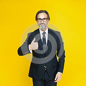 Handsome mature businessman in black suit. Showing thumb up middle aged business man smiling looking at camera isolated