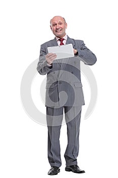 Handsome mature businessman in formal suit is using a digital tablet, looking at camera and smiling