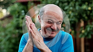 A handsome mature man in blue shirt laughing rubbing hands fairly.