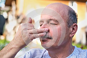 Handsome mature man breathing yoga pranayama on summer sunny day outside.