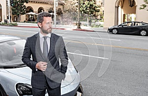 handsome mature man in businesslike suit stand by luxury car outdoor, copy space, success.