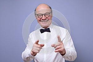 Handsome mature man in glasses pointing at camera pointing at you