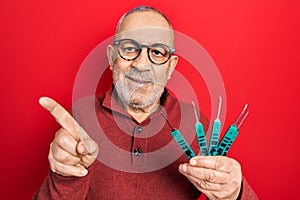 Handsome mature man holding picklock to unlock security door smiling happy pointing with hand and finger to the side