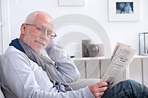 Handsome mature man reading newspaper on sofa