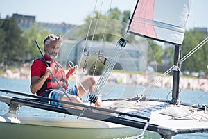 handsome mature man sailing on hobie catamaran