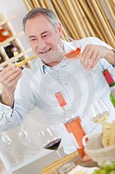Handsome mature man tasting glass rose wine