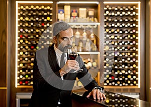 Handsome mature man tasting red wine