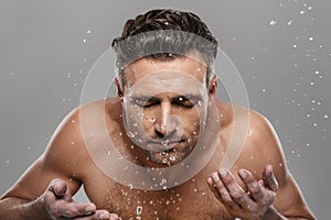 Handsome mature man washing his face.