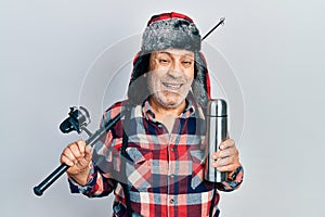 Handsome mature man wearing fisherman equipment and thermo smiling and laughing hard out loud because funny crazy joke