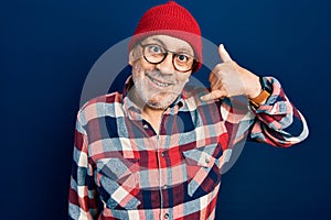 Handsome mature man wearing hipster look with wool cap smiling doing phone gesture with hand and fingers like talking on the