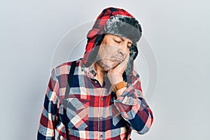 Handsome mature man wearing winter hat with ear flaps thinking looking tired and bored with depression problems with crossed arms