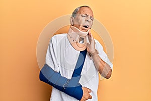 Handsome mature senior man wearing cervical collar and arm on sling touching mouth with hand with painful expression because of