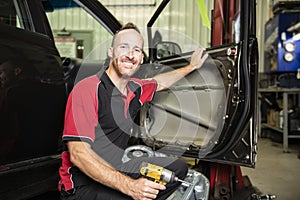 Handsome mechanic based on car in auto repair shop