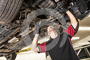 Handsome mechanic based on car in auto repair shop