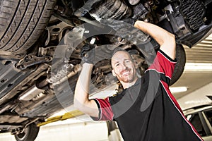 Handsome mechanic based on car in auto repair shop
