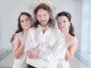 Man in medieval costume and two beautiful woman in old-fashioned negligee