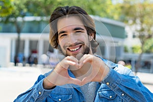 Handsome mexican young adult man in love gesturing heart