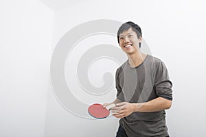 Handsome mid adult man holding table tennis paddle
