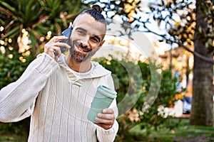 Handsome middle age man with beard standing happy and confident outdoors having a conversation speaking on the phone