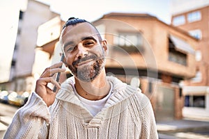 Handsome middle age man with beard standing happy and confident outdoors having a conversation speaking on the phone