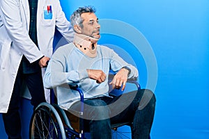 Handsome middle age man with grey hair on wheelchair wearing cervical collar looking to side, relax profile pose with natural face
