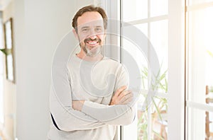 Handsome middle age man smiling looking at the camera at home
